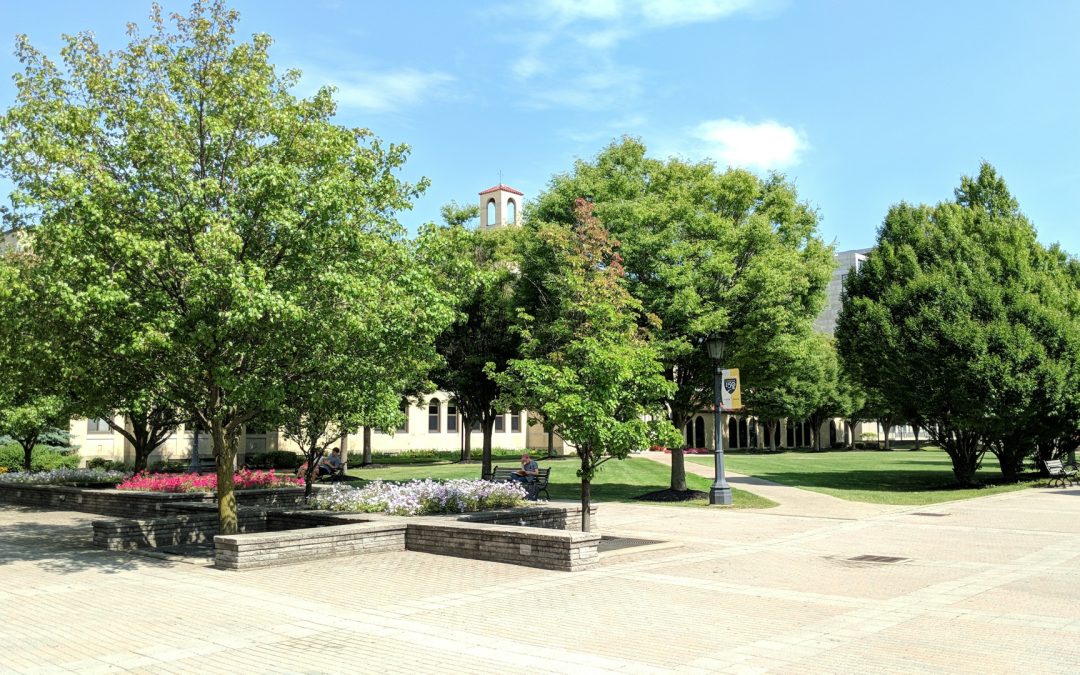 Loyola Hall hidden by trees in Summer.